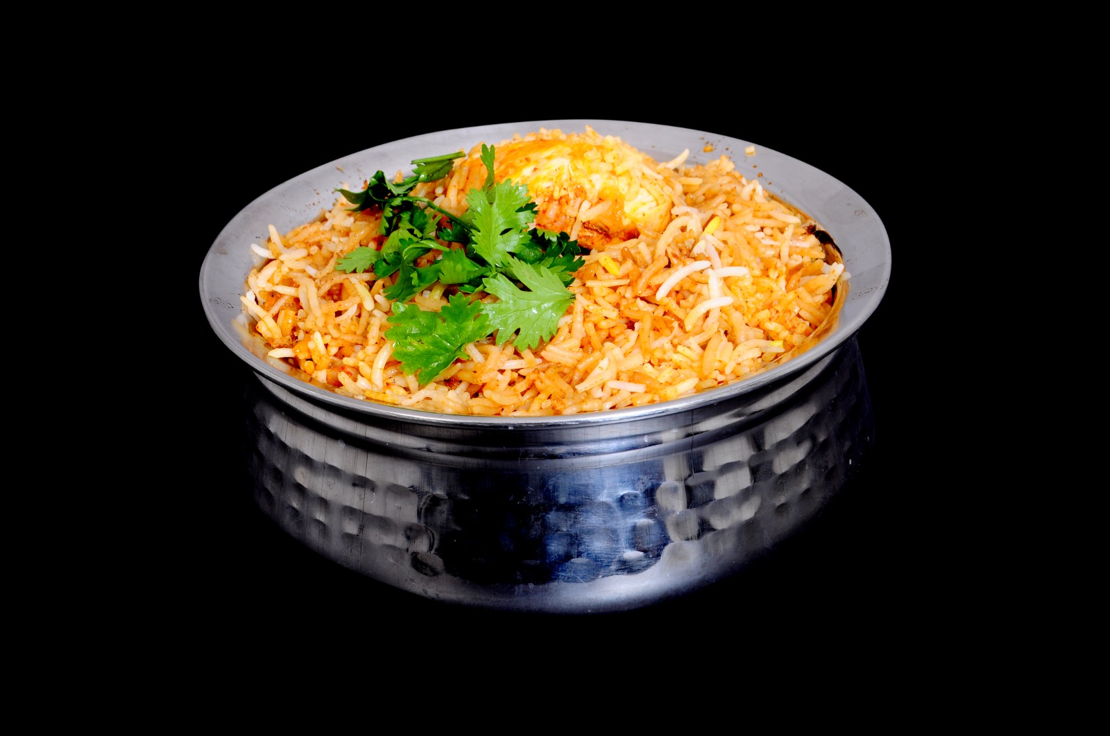 Chicken Hyderabadi Dum Biryani in a handi, topped with a golden egg and coriander