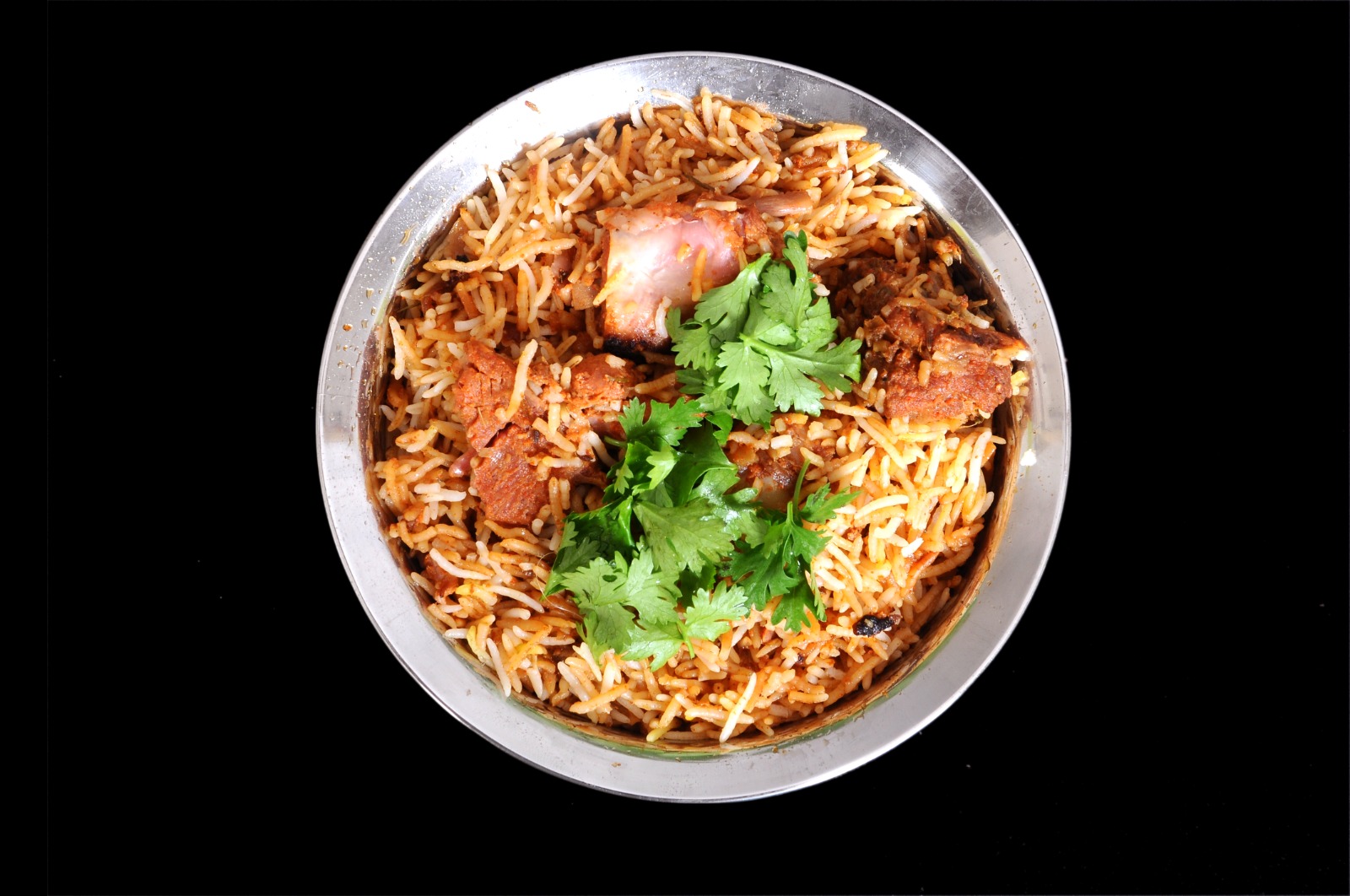 Mutton Hyderabadi Dum Biryani, top-down in a steel plate with fresh coriander