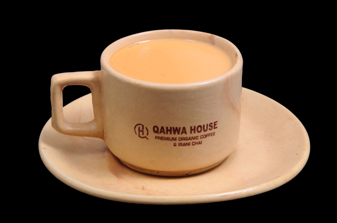 Qahwa House Irani chai — strong milky tea in a branded cup and saucer